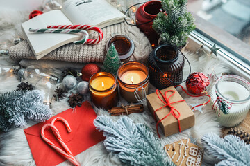 Festive New Year's home decor on the windowsill, burning candles, open book and decor