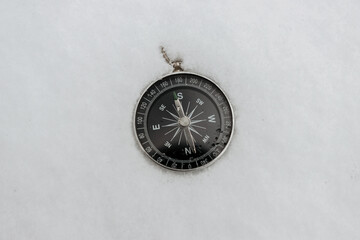 Round compass in the snow, space for text. Navigation in the winter forest. Orienteering concept in...