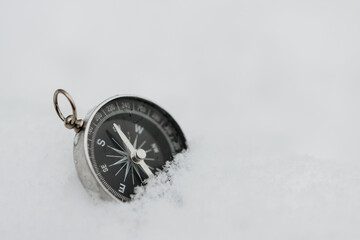 Round compass in the snow, space for text. Navigation in the winter forest. Orienteering concept in the winter forest