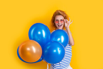 party girl with balloon in sunglasses. happy girl having fun hold party balloons in studio.