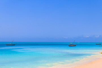Obraz premium View of tropical sandy Nungwi beach and traditional wooden dhow boats in the Indian ocean on Zanzibar, Tanzania
