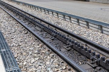 Selective focus, diagonal view of trail tracks in the Swiss alps. The middle track is known as a cog wheel and help train go up and down mountains. 
