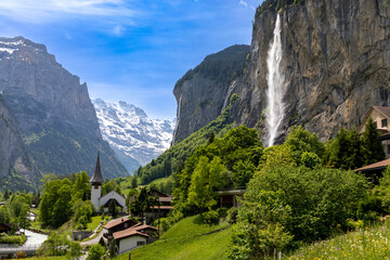 Fototapeta na wymiar Landscape view of a part of Lauterbrunnen in Switzerland. Snow covered Alps in the background and the Staubbach waterfall on the right. 