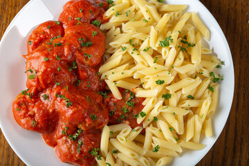 Pasta with meatballs in tomato sauce with herbs - top view