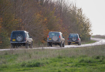 Plakat three modified off road 4x4 vehicles driving along a mud track, Wilts UK