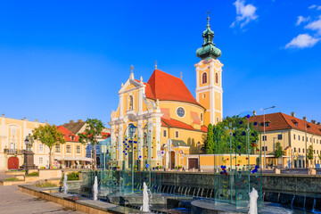Gyor, Hungary. Carmelite Church and water fountain. - obrazy, fototapety, plakaty