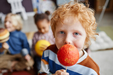 Adorable boy with ginger hair holding model of Mars planet and looking at camera while playing...