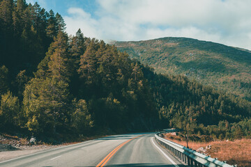 A road in Norway surrounded by trees and mountains