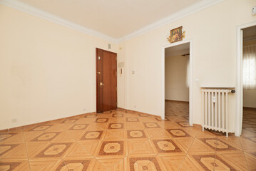 Empty room with plain white painted walls, blacon painted wrought iron radiators and brown...