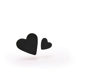 Two black hearts floating isolated on white background.
