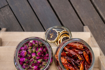 glass jars filled with dehydrated products, chilli peppers, tea roses and citrus slices