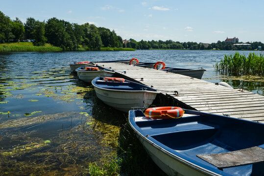 many boats at the pier on the lake lifebuoys. mud on the water lithuania trakai 24 july 2022
