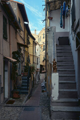 A narrow street with colourful buildings and laundry hung to dry in an old town in Europe. Ventimiglia, Italy
