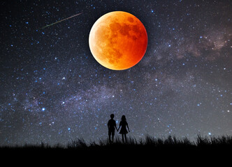 皆既月食で赤く染まった月を見上げるカップルのシルエット