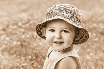 Happy toddler baby boy sit on grass in nature, black and white. Smiling child in shirt and hat...
