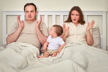Fototapeta premium Frightened woman and a man with problems after the birth of a toddler baby on the bed