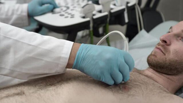 Ultrasound: A doctor checks a man's chest with an ultrasound machine. Diagnosis of respiratory lung and heart diseases. Examination of the body in the clinic office. Checking the status of sonograms