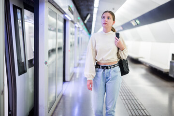Portrait of a focused and confident girl standing on a subway station platform. Close-up portrait