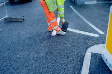 Road workers applying hot melt traffic resistant paint for white, yellow and red road marking lines...
