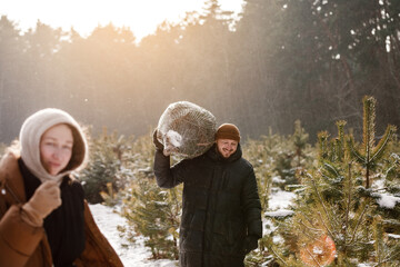 Love romantic young couple woman, man in snowy winter forest with fir tree. Walking, having fun,...