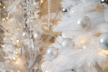 A white Christmas tree is decorated with silver plastic toys. Bright festive decoration for the new...