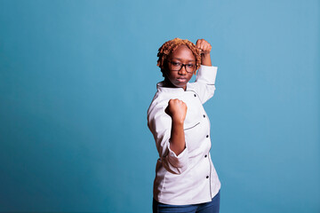 African american chef ready to fight with blows. Angry, furious female kitchen worker using glasses, curly hair. Female cookers team member upset for work related argument.