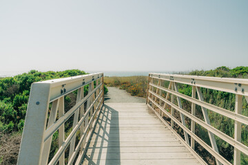 Wooden boardwalk leading  to the beach, and clear blue sky on background, copy space
