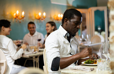Confident african american man having lunch in a restaurant - eating a delicious healthy salad