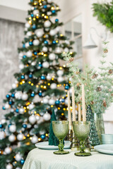 The table is set near the Christmas tree for a romantic New Year's dinner. New Year's festive dinner.