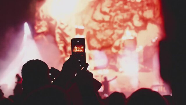 Fans are holding a smartphone, taking photos and videos. Night club or music concert. Records a concert for social networks. Strobing stage lights. Happy people at the concert.