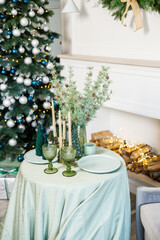 The table is set near the Christmas tree for a romantic New Year's dinner. New Year's festive dinner.