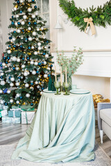 The table is set near the Christmas tree for a romantic New Year's dinner. New Year's festive dinner.