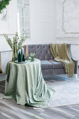 Table setting for Christmas or New Year's dinner with candles, decorations, tablecloth and napkins on the background of a Christmas tree in an apartment
