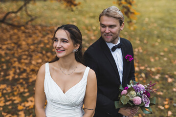 Outdoor autumn portrait of happy smiling ethnic heterosexual newlyweds in their wedding clothing...