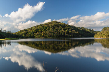 a beautiful view of a mountain with trees and a sky with clouds reflected in a lake