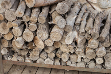 Firewood stacked against a wall on a metallic shelf.