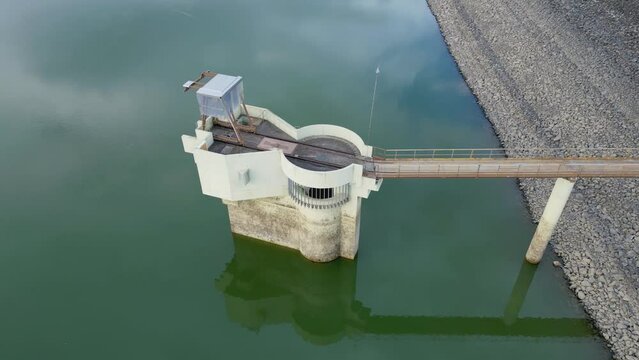 Water intake tower of the Michelbach lake dam (Upper-Rhine, Alsace, France) in 360 degrees rotation aerial drone close view for all faces, by drought weather in summer with a very low water level