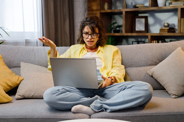 Young female freelancer, stressed out from working online. Focused girl uses laptop for nervous conversation and consultations online at home, female user, remote work on the Internet, programming