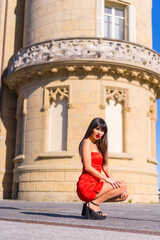 Portrait in red dress in beautiful castle, attractive girl, crouching portrait