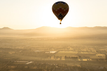 A Hot Air Balloon rises above the countryside as the sun rises