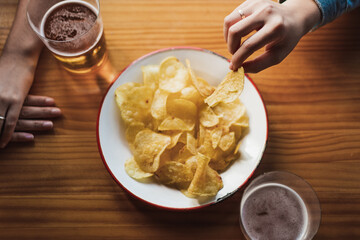 Close up of a woman taking a chip from the plate to eat it. She is in a bar with a friend.