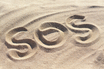 SOS message written on sandy beach outdoors
