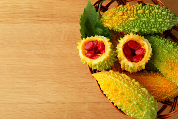 Basket with fresh bitter melons on wooden table, top view. Space for text