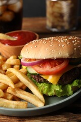Delicious burger, soda drink and french fries served on wooden table, closeup