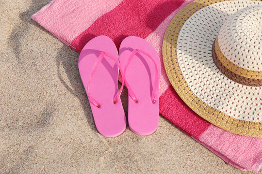 Beach towel with straw hat and slippers on sand