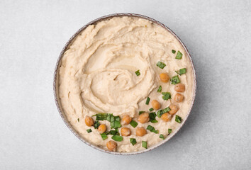 Bowl of delicious hummus with chickpeas on light grey table, top view