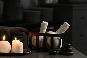 Fototapeta na wymiar Herbal massage bags, burning candles and stones on grey table. Spa products