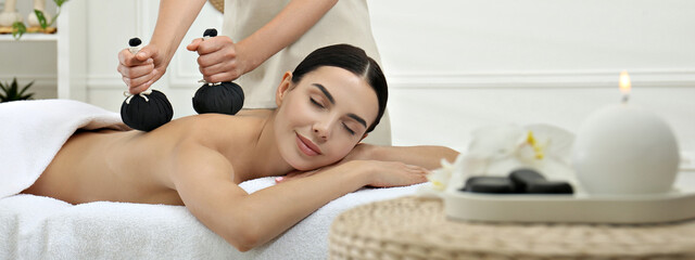 Young woman receiving herbal bag massage in spa salon. Banner design