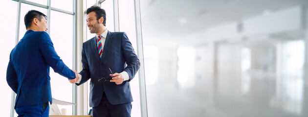 Business people handshake in corporate office in widen view showing professional agreement on a financial deal contract.