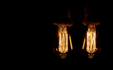 Old tungsten light bulb with their golden glow suspended with thick rope hangers